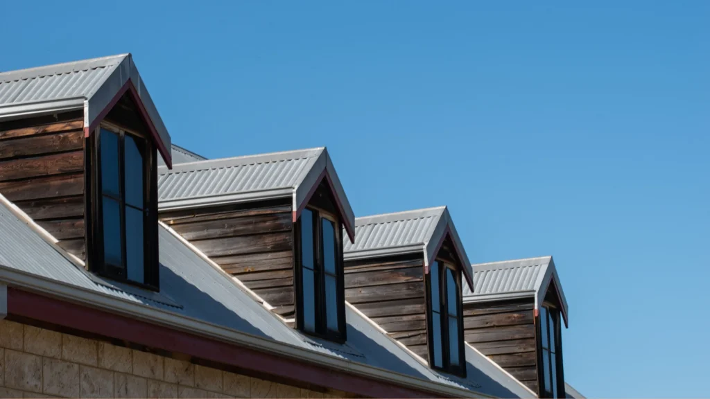 Light grey Colorbond corrugated metal roof with dormer windows against blue sky