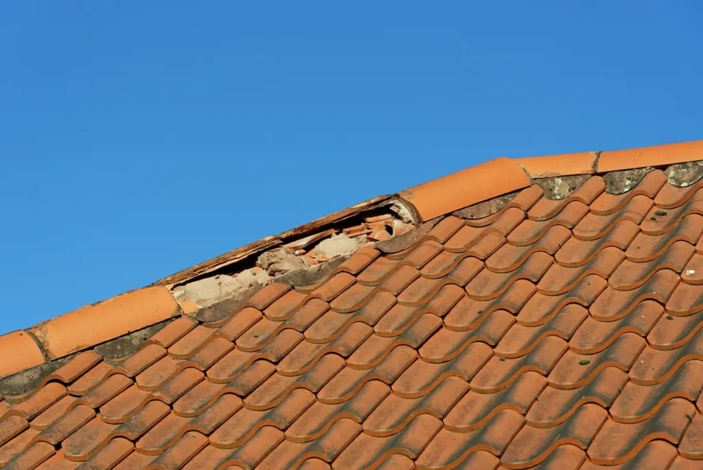 Cracked and slipped roof tiles with damaged ridge caps on a Melbourne tiled roof.